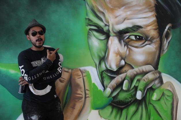 Azlan posing beside his half-finished graffiti piece.